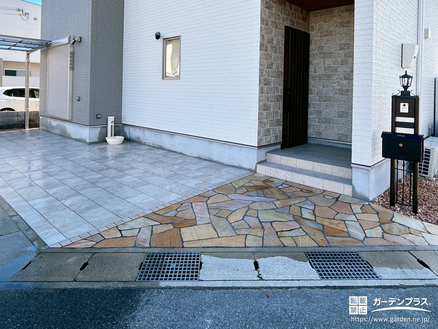 駐車スペースのタイルとアプローチの乱形石が映える外構