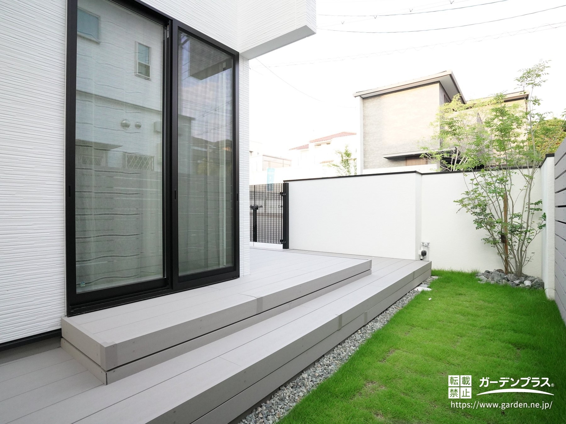 明るいグレーのウッドデッキと植物が調和したお庭