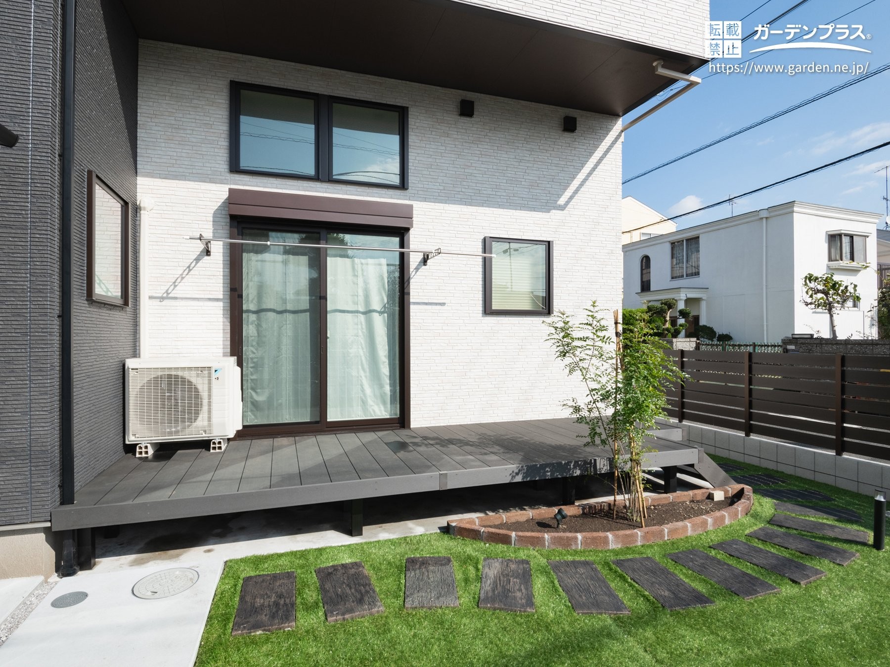 ツートン外壁に調和するグレーのウッドデッキ