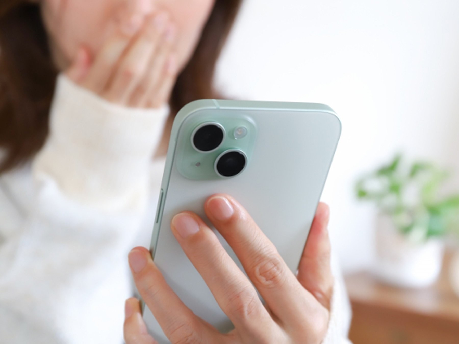 スマホニュースを見て驚く女性