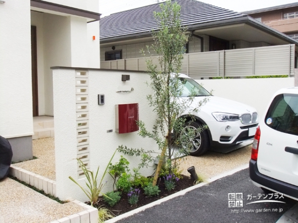 白い門柱に赤いポストの映える花壇つきの門まわり