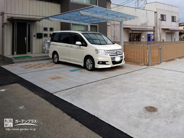 カーポートと白基調のタイルに暖色を織り交ぜた駐車スペース