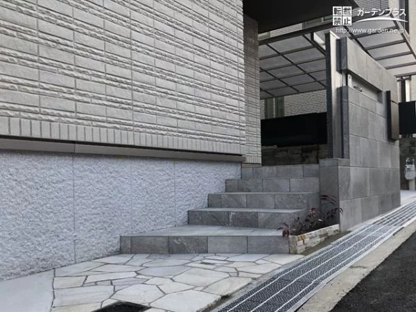 乱形石のアプローチとタイル貼の玄関ポーチ階段
