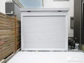 駐車スペース後方のシャッター付きガレージ(イナバ物置 ドマール 一般型 床付タイプ FF-2626HY クールシルバーCS)