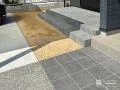 グレーのタイル貼りで洗練された雰囲気のデッキとアプローチ