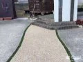 両脇に入れた人工芝の目地が可愛らしく映える玄関アプローチ工事
