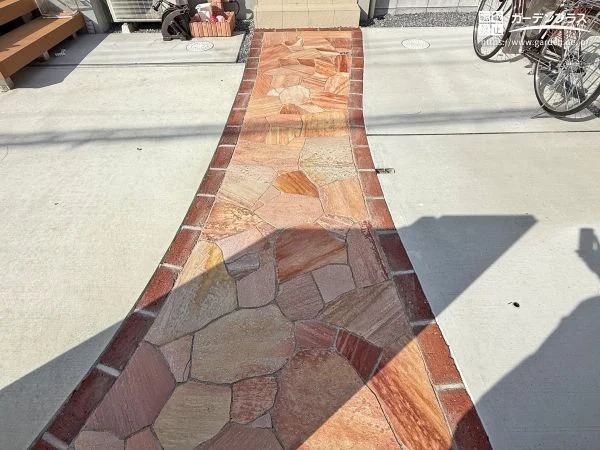 赤みを帯びた天然石が華やぎをもたらすアプローチ