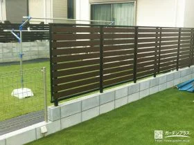 人工芝の緑に映える木目調フェンスで視線をカットした工事