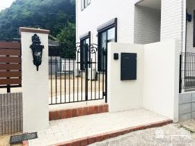 上品なアイアン門扉とクラシカルな照明がこだわりの門まわり[施工後]