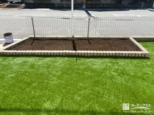 レンガの花壇が可愛らしいアクセントになった人工芝のお庭工事