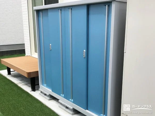 爽やかなブルーの物置が緑鮮やかな人工芝のお庭に映える工事