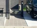 玄関まで続くアプローチはタイル仕上げとし、住まいの入口に上質な印象をつくりました。機能門柱と宅配ボックスを一体にまとめることで、荷物の受け取りや来客対応もスムーズに。玄関ポーチの階段も同じタイルで仕上げ、アプローチから玄関まで素材を統一することで、すっきりとしたファサードに整えています。
