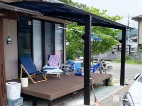 屋根付きのウッドデッキと鮮やかなブルーの物置を設置した工事