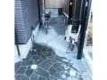 洗い出しコンクリートと乱形石張りで、駐輪スペースも兼ねたアプローチ