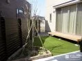 レンガで囲んだ植栽スぺースがアクセントの人工芝敷きのお庭工事