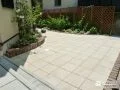やさしいベージュの平板が草花を包む明るく華やかなお庭工事