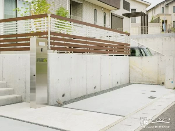 土間コンクリートと砕石敷きのモノトーンデザインの駐車スペース