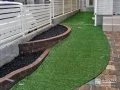 優しい曲線を描いたレンガ花壇と人工芝のお庭