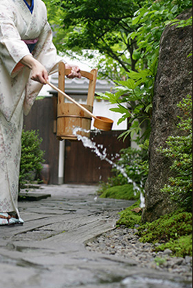 [写真]打ち水をする和服の女性