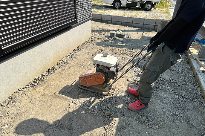 土間コンクリート沈下防止のために敷いた砕石を転圧機で押し固める様子