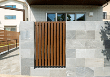 天然石のようなデザインに木目調の目隠しフェンスを組み合わせたデザイン塀